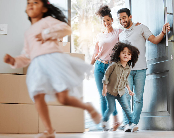 Happy, moving and parents with children running in their new modern family house with excitement. Happiness, smile and young mother and father watching their kids jumping in blur motion at their home. - Photo, image