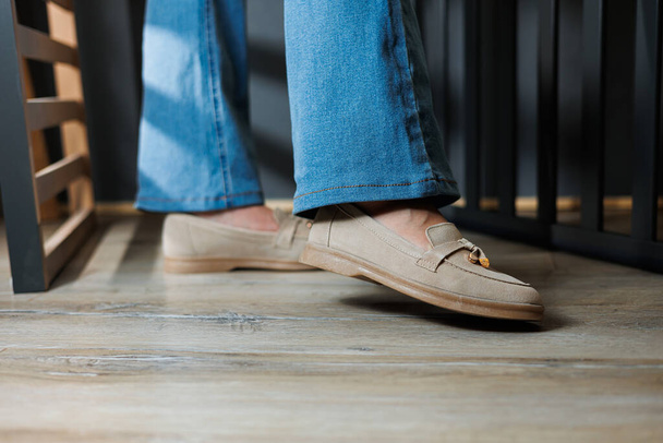 Close-up van vrouwelijke benen in jeans en beige loafers van echt leer. - Foto, afbeelding