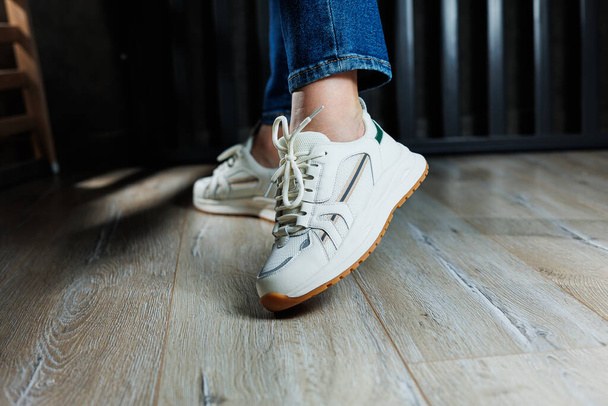 Piernas delgadas de mujer primer plano en jeans y zapatillas blancas hechas de cuero genuino. - Foto, imagen