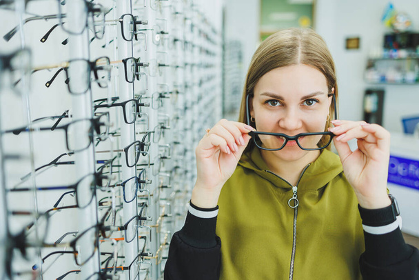 Egy fiatal nő szemüveget választ a látásjavításhoz. Szemészeti bolt szemüveggel a látás javítása érdekében. - Fotó, kép