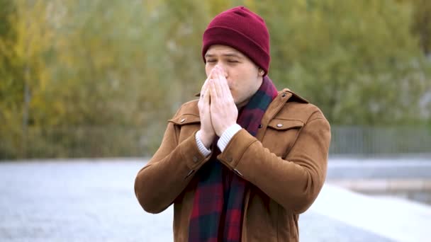 Latin fiatalember dörzsöli a kezét, köhög és orrát a szövetekbe fújja télen. Hideg idő. Influenza. - Felvétel, videó