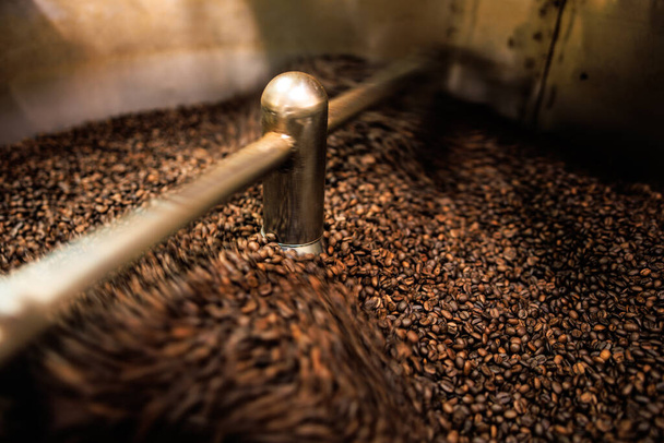 fresh coffee beans roasted spinning cover professional machine close up to soft focus  slow shutter speed because want to make motion blur of coffee beans detail concept, at factory chiang rai Thailand, angle view shot. - Valokuva, kuva