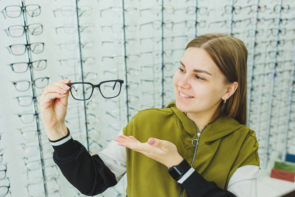 Egy fiatal nő szemüveget választ a látásjavításhoz. Szemészeti bolt szemüveggel a látás javítása érdekében. - Fotó, kép