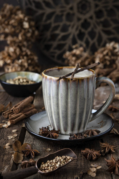 Mug of traditional indian masala chai tea with ingredients: cinnamon, cardamom, anise, nutmeg - Foto, Bild