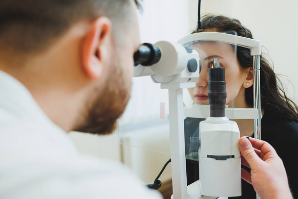 Examination of vision on modern ophthalmological equipment. Eye examination of a woman at an ophthalmologist's appointment using microscopes. Vision treatment at an ophthalmologist appointment - Foto, Imagen