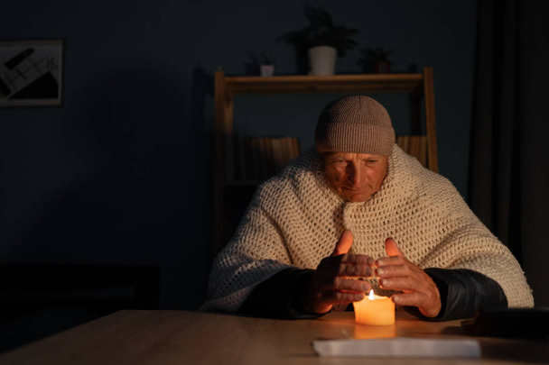 Vanha mies kärsii ilman lämmitystä ja sähköä energiakriisin aikana aiheuttaa sähkökatkoksia. Ei lämmitystä. Kopioi tila - Valokuva, kuva