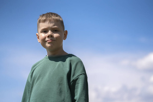 Retrato de um menino loiro de oito anos contra o céu com espaço para texto. Foto de alta qualidade - Foto, Imagem