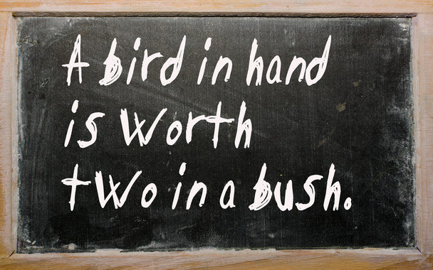 "Ein Vogel in der Hand ist zwei im Busch wert "steht auf einer Tafel geschrieben - Foto, Bild