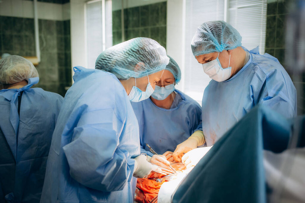 Un chirurgien recoud un patient dans la salle d'opération. - Photo, image