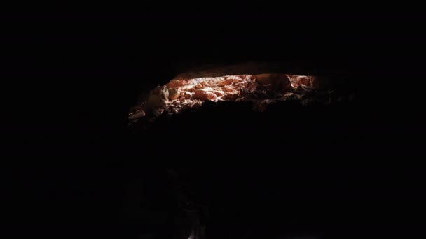 Um grupo de pessoas caminha em uma única linha de arquivo, saindo de uma caverna após uma visita guiada. A caverna é escura, com espaço para texto, e eles caminham em direção à luz de forma ordenada. . - Filmagem, Vídeo