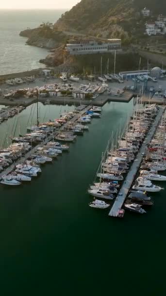 Uchwyć kinowy widok jachtów zacumowanych przy porcie morskim Alanyas podczas pięknego zachodu słońca w tym pionowym filmie. - Materiał filmowy, wideo
