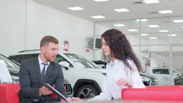 Happy brunette woman buying a luxury car. The car sales manager prepares the documents. Car sales concept - Footage, Video