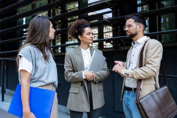 Business people partners colleagues team and staff member last meeting and discussion before summer vacation break. Businessman with two expert businesswomen strategy talk outside office building - Foto, Imagen