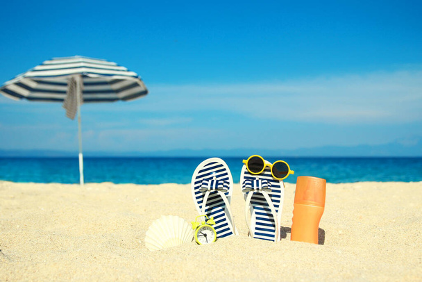 Beach summer holiday banner background. Flip-flops and hat with a board and ball on the sand near the ocean. Summer accessories on the seashore. Tropical vacation and relax travel concept. Top view and copy space. - Foto, Imagen