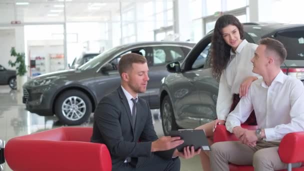 A lovely couple is talking to a manager while buying a car at a car dealership. Car dealership. - Imágenes, Vídeo