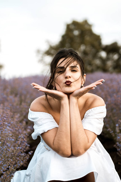 Young woman in a white dress posing in a lavender field.The concept of a photo shoot in lavenders - Zdjęcie, obraz