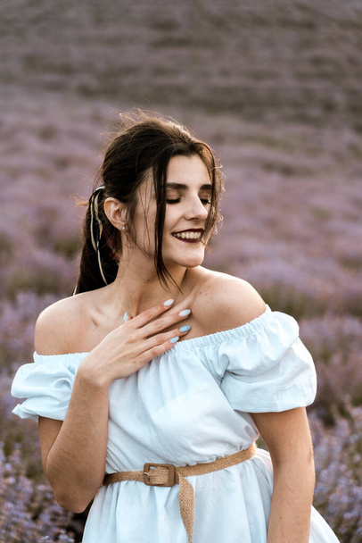 Young woman in a white dress posing in a lavender field.The concept of a photo shoot in lavenders - Foto, immagini