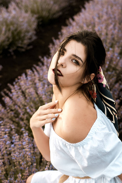Young woman in a white dress posing in a lavender field.The concept of a photo shoot in lavenders - Fotó, kép
