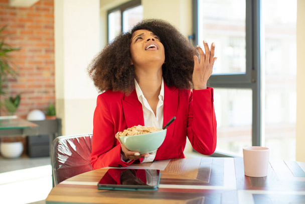 pretty afro black woman screaming with hands up in the air. having breakfast concept - Foto, Imagem