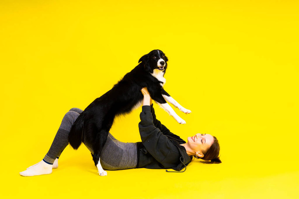 Shot of sport female in leggings with a border collie dog isolated on yellow and red background - Photo, Image