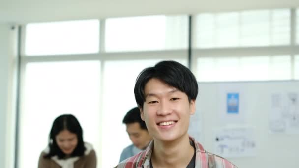 Tilt down shot of asian male web developer holding digital tablet and smiling to camera. - Footage, Video