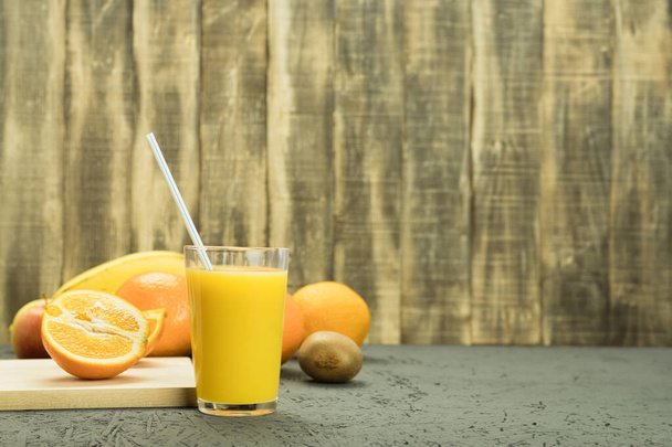 Fresh orange juice in a glass with a straw. Rural background. Citrus juice - Zdjęcie, obraz
