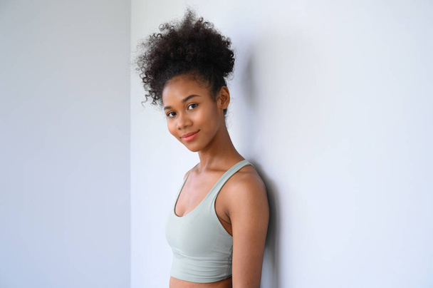 Piękna młoda Afroamerykanka pozowanie z ubraniami fitness na białym tle. Koncepcja zdrowia i sprawności - Zdjęcie, obraz