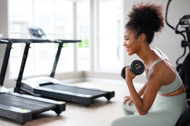 Sporty fitness African American woman working out with dumbbells strength and strength endurance at the gym - Foto, Imagen