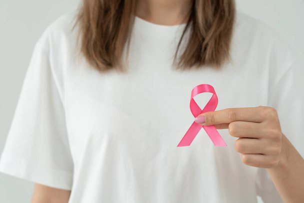 Γυναίκα κατέχει ροζ κορδέλα ευαισθητοποίησης για τον καρκίνο του μαστού. Γυναικεία συνείδηση ελέγχου υγείας. Παγκόσμια Ημέρα της Γυναίκας και Ημέρα του Καρκίνου. σημάδι του καρκίνου, Συμβολικό, υγειονομική περίθαλψη, υποστήριξη ασθενών, έγκαιρη διάγνωση - Φωτογραφία, εικόνα