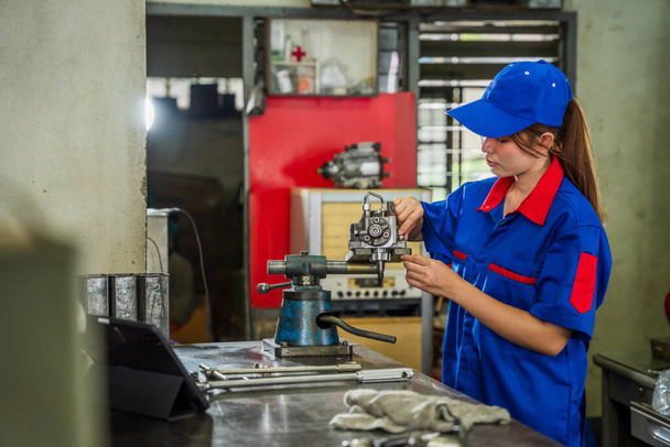A female diesel engine mechanic in a blue uniform is working at the garage. Inspect and maintain the fuel pressure booster pump system and common rail injectors. - Foto, Imagem