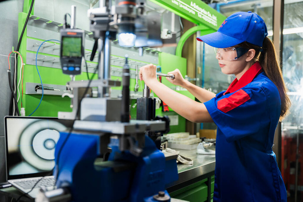 A female diesel engine mechanic in a blue uniform is working at the garage. Inspect and maintain the fuel pressure booster pump system and common rail injectors. - Фото, изображение