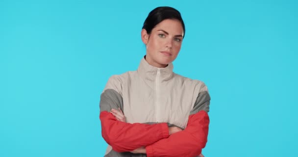 Fitness, coach and woman face with arms crossed in studio serious, tough and ready on blue background. Portrait, attitude and female personal trainer proud of workout, training or healthy lifestyle. - Footage, Video