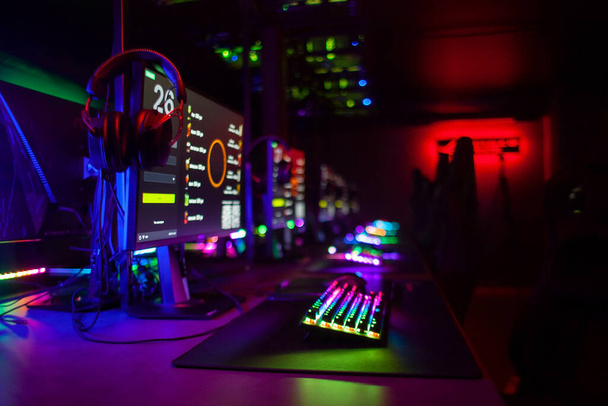 bilgisayar kulübü, monitörler, klavyeler, neon ışıklı sandalyeler ve kulaklıklar, siber oyuncular cihazları ve ekipmanları - Fotoğraf, Görsel