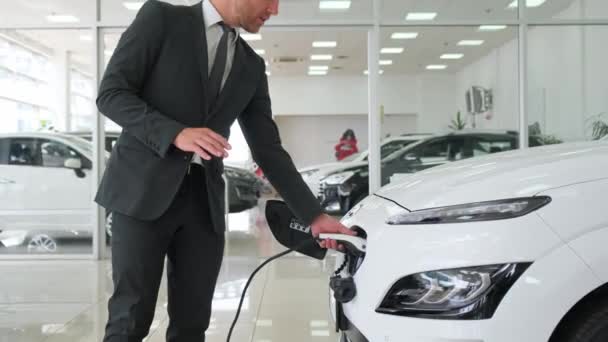 A car sales manager talks about a modern charging system for electric cars. Car sales salon - Filmati, video