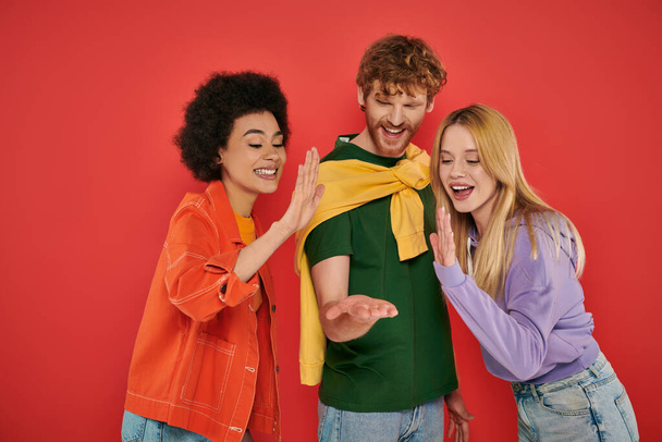 open relationship, polygamy concept, three interracial lovers giving high five on coral background, cultural diversity, polyamorous, excited multiethnic people having fun  - Foto, Imagen