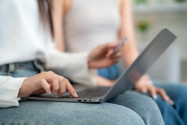 Close up hand of women shopping online shopping on laptop with credit card while sitting on sofa in living room. online shopping concept. - Foto, Imagen