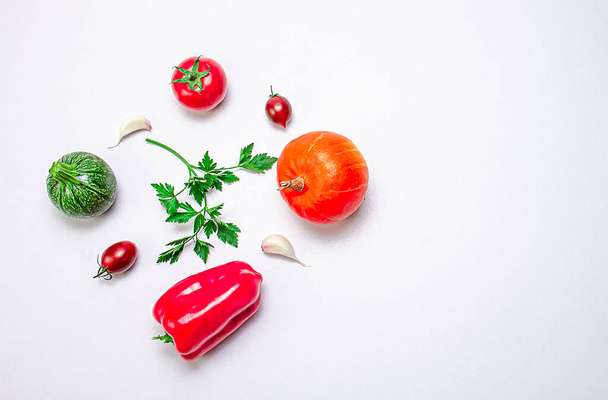 Kreative Komposition aus Kürbis, Auberginen, Paprika, Sherry-Tomaten, Knoblauch und Zucchini auf weißem Hintergrund. Food-Konzept. Gesunde Ernährung. Blick von oben. Kopierraum. - Foto, Bild