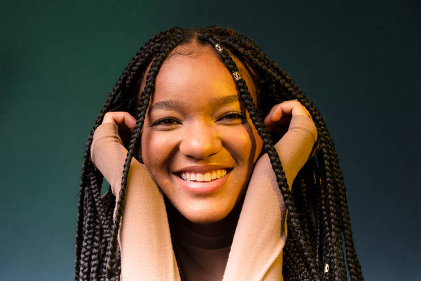 Retrato de una joven sonriente con coletas, con las manos en la barbilla. Aislado sobre fondo cian oscuro. - Foto, Imagen