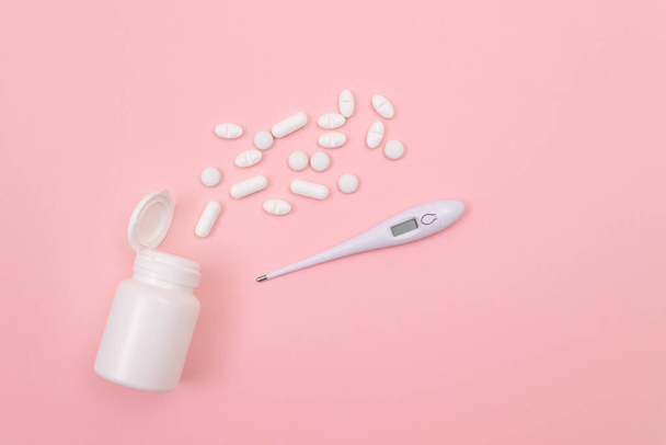 White Pills or Tablets with Electronic Thermometer on Pink Background. Pharmaceutical Industry and Medicinal Products - Φωτογραφία, εικόνα