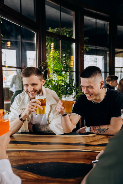 醸造所のバーレストランでビールやカクテルを飲みながらお友達の幸せなグループ。男性と女の子が一緒に楽しみを持っていると飲料ライフスタイルの概念 - 写真・画像