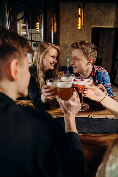Fröhliche Gruppe von Freunden trinkt und klimpert bei Bier und Cocktails im Brauerei-Bar-Restaurant. Beverage Lifestylekonzept mit Jungs und Mädchen, die gemeinsam Spaß haben - Foto, Bild