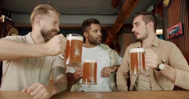 Grupa przyjaciół pije piwo, rozmawia i dobrze się bawi w pubie. Koledzy w dobrym nastroju piją piwo i relaksują się. Wielorasowych Przyjaciół korzystających z weekendowej nocy w barze - Materiał filmowy, wideo