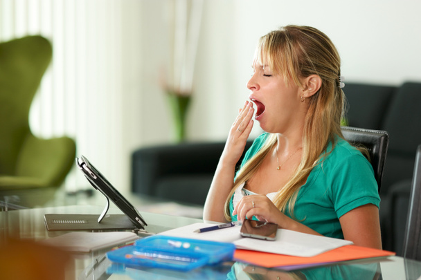Mujer joven estudiante bostezando mientras estudia
 - Foto, imagen