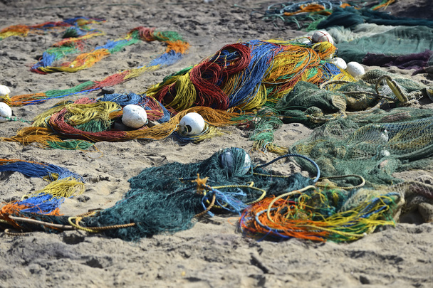 Fisher pile up fishing net on the beach - a Royalty Free Stock