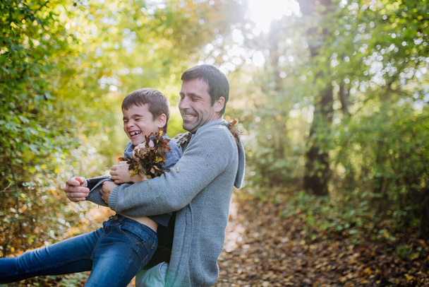Father with his children having fun in forest, throwing foliage. - Fotografie, Obrázek