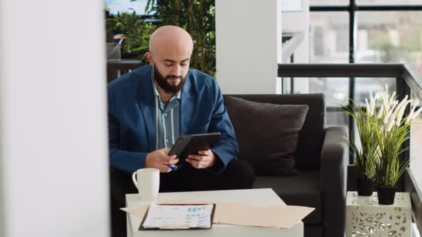 Middle eastern man takes notes on tablet, creating new investment strategy to increase profit. AI developer works on programming analytics, reading server script in small business office. - Footage, Video