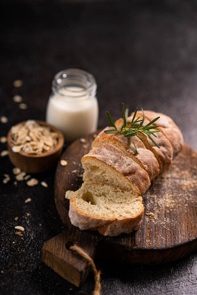 Sliced baguette bread on wooden coaster and rustic background. Artisan Sourdough bread. - Valokuva, kuva