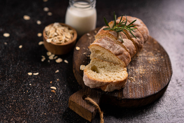 Sliced baguette bread on wooden coaster and rustic background. Artisan Sourdough bread. - Fotografie, Obrázek