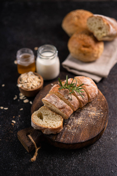 Sliced baguette bread on wooden coaster and rustic background. Artisan Sourdough bread. - Фото, изображение
