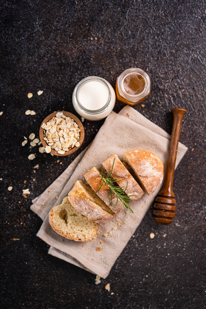 Sliced baguette bread on wooden coaster and rustic background. Artisan Sourdough bread. - Foto, imagen